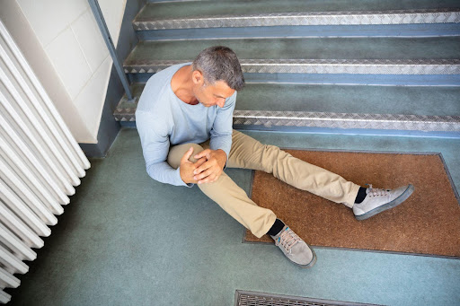 A man clutching his injured knee after a slip and fall