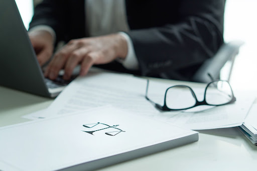 man on laptop near paper with scales of justice print